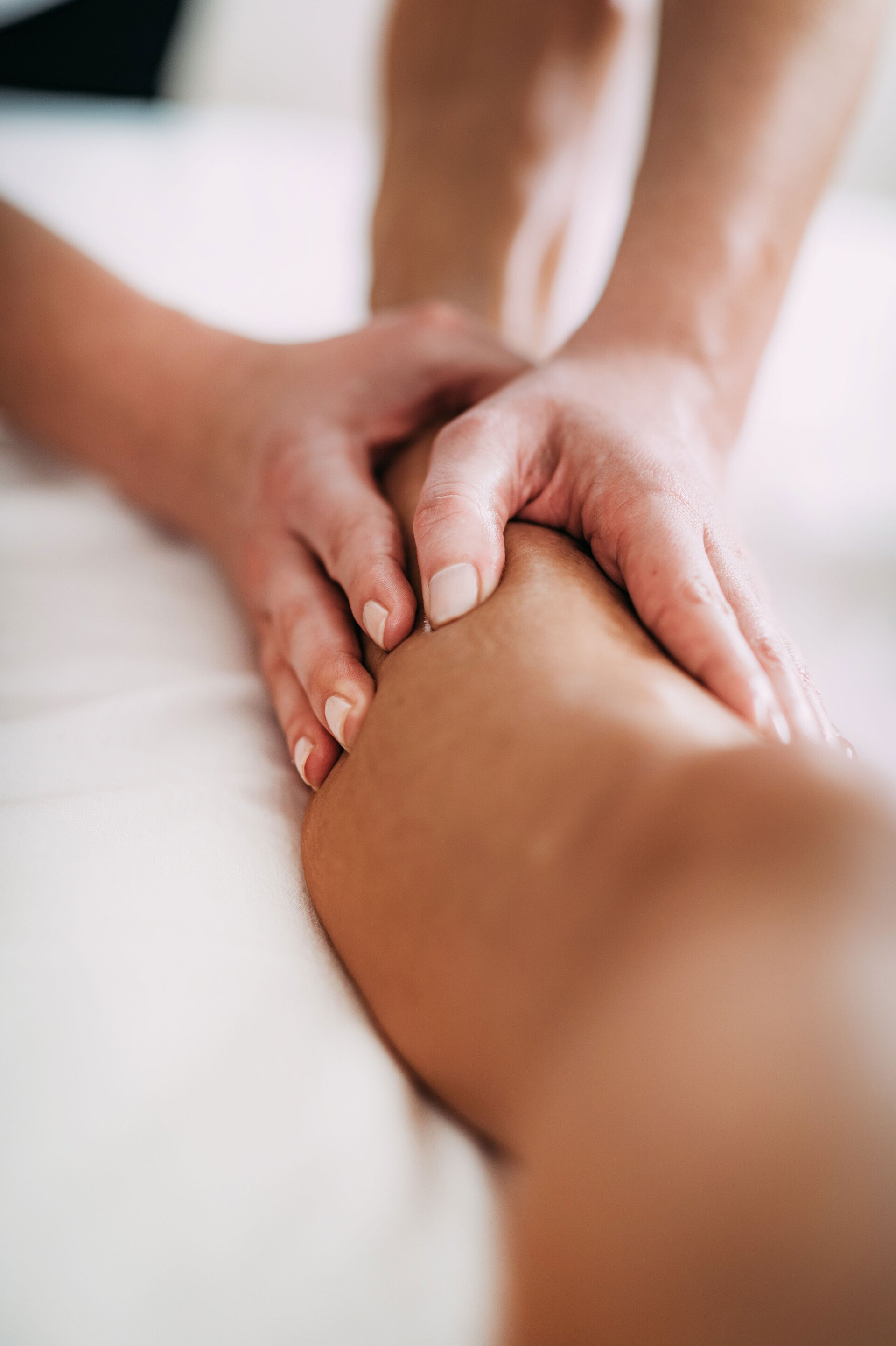 Hautprodukte können auch zur Massage eingesetzt werden, wie dieses Bild von zwei massierenden Händen auf einer Wade zeigt.