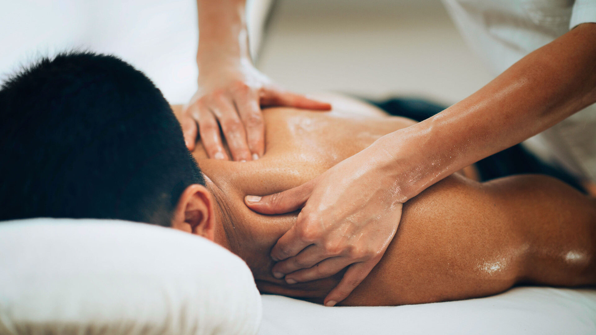 Eine liegende Person erhält zur Lockerung der Muskeln und Gelenke eine Massage.