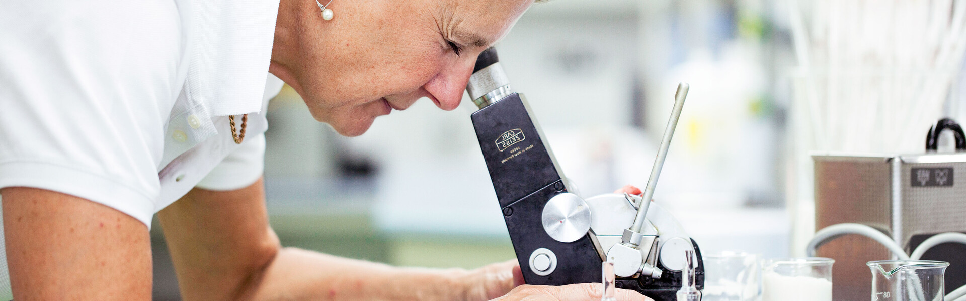Forscherin beugt sich über Mikroskop. Die Sixtus-Forschung entwickelt Hautpflege für die Zukunft weiter.