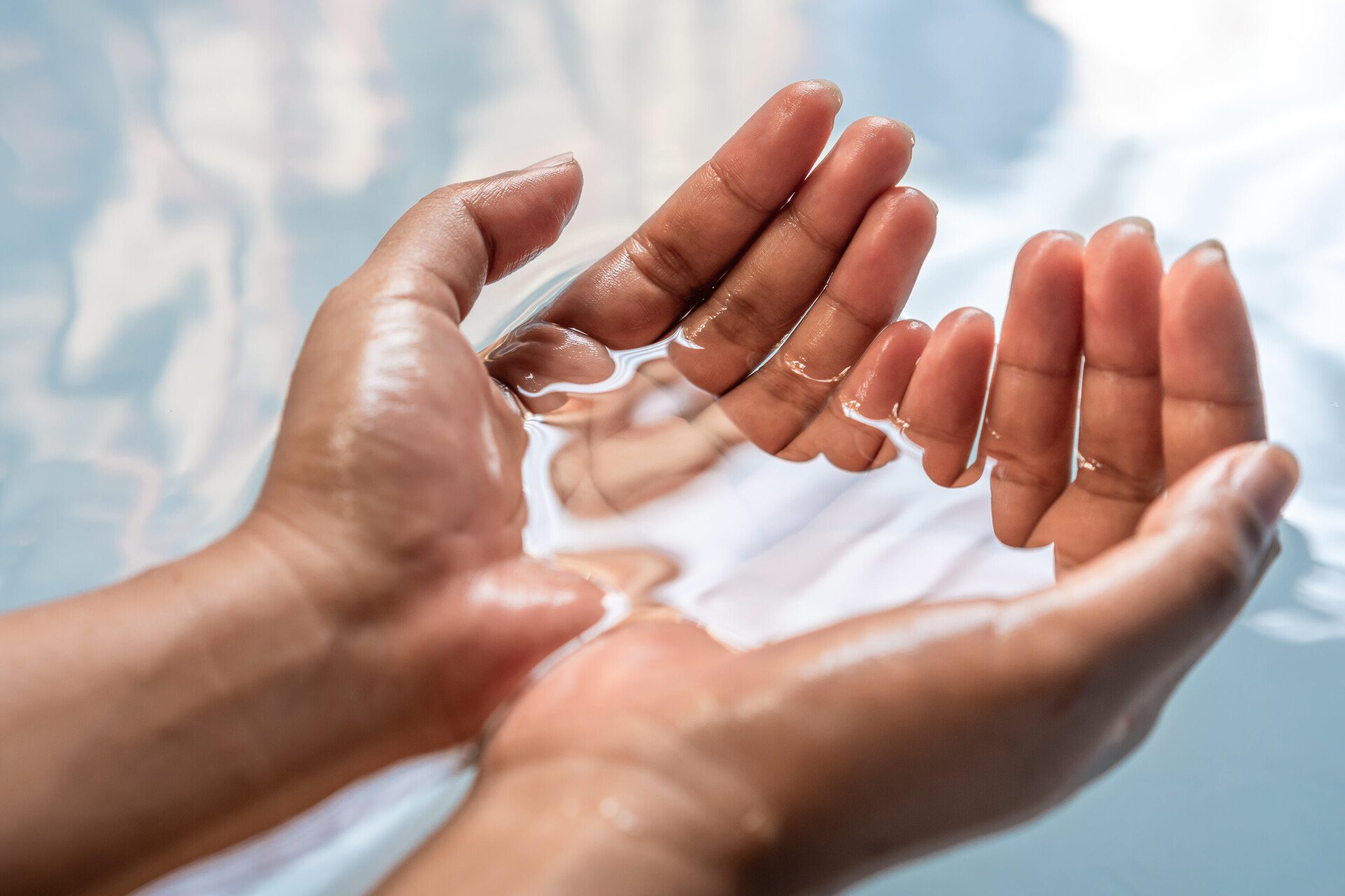 Zwei Hände schöpfen Wasser. Das Bild steht für das Handbad – einen wichtigen Bestandteil der Nagelpflege.